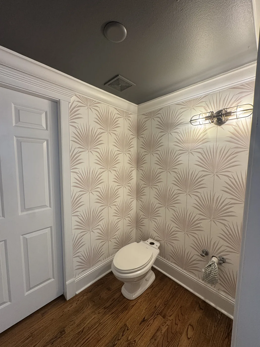 Pale palm wallpaper wrapping around a powder room corner