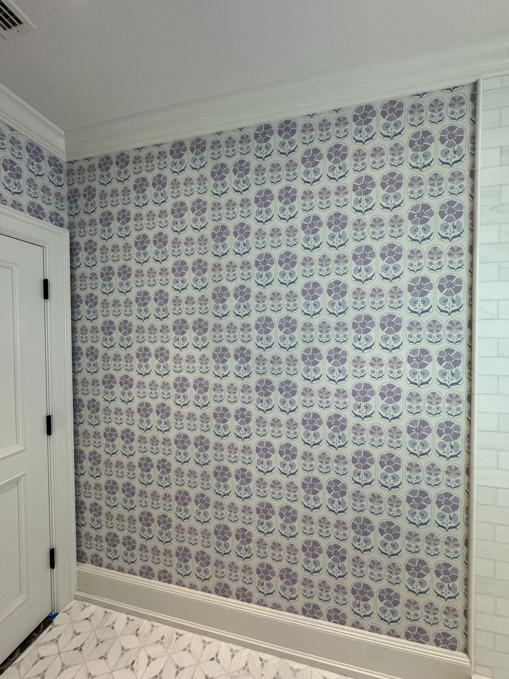 Blue and lavender repeating floral wallpaper aligned across an accent wall