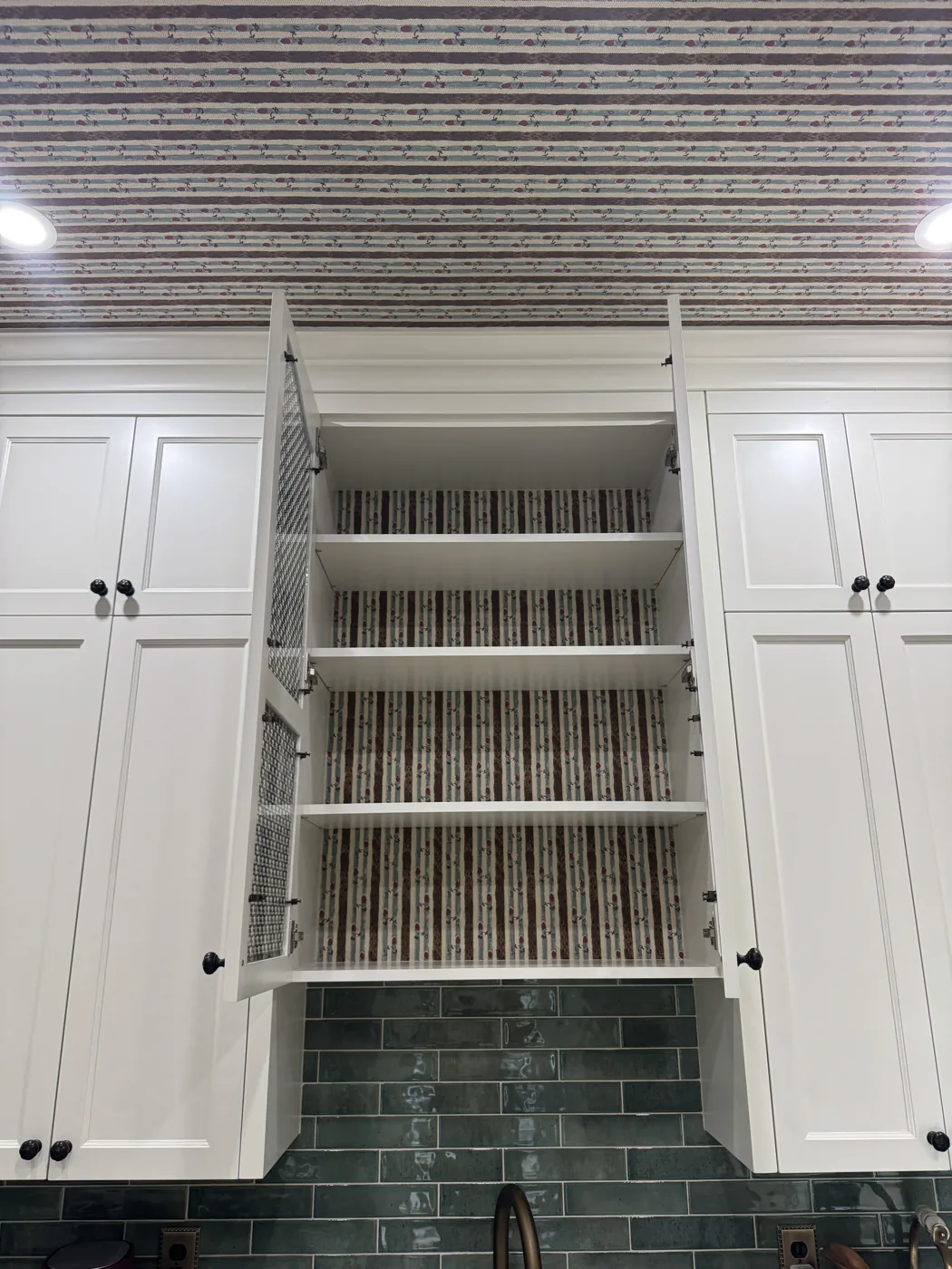 Striped wallpaper installed on a ceiling and inside kitchen cabinetry